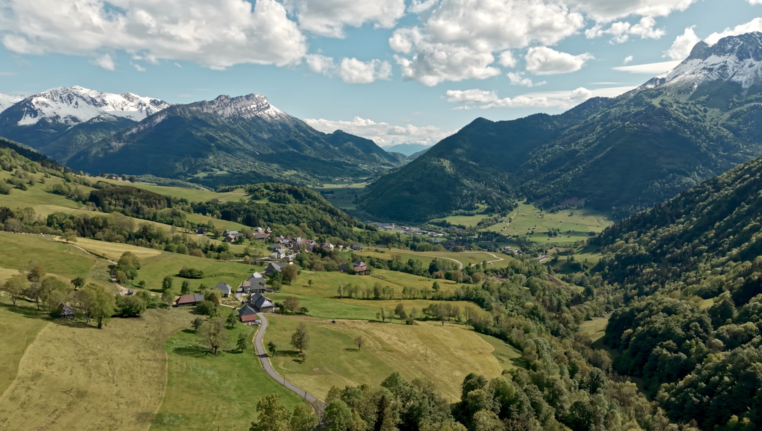 Vue aérienne sur un village du massif des Bauges entouré de montagnes